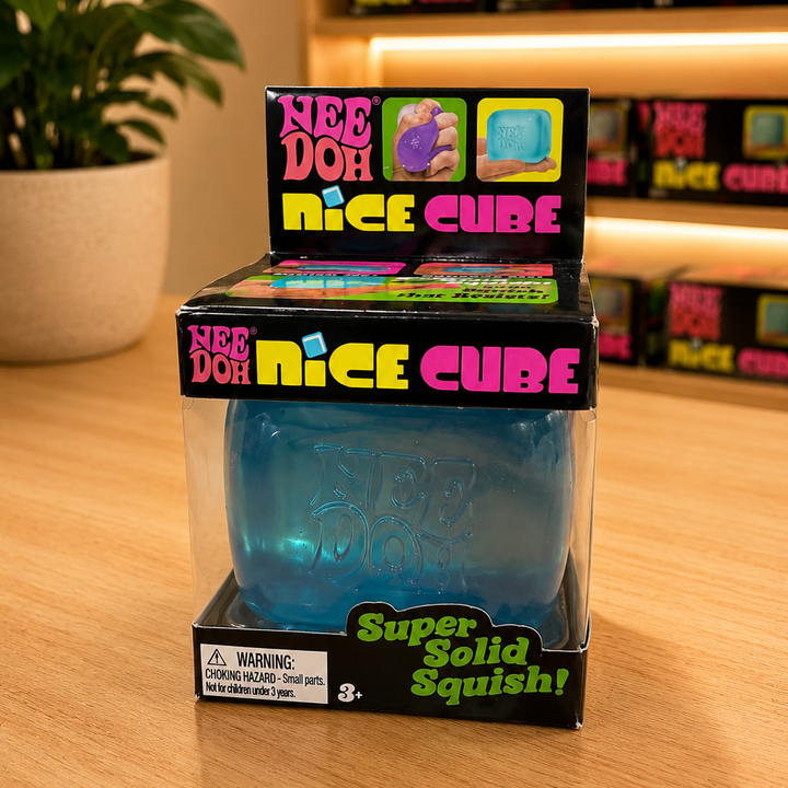 Blue gummy cube in packaging with 'Nee Doh Nice Cube' branding on a wooden surface.